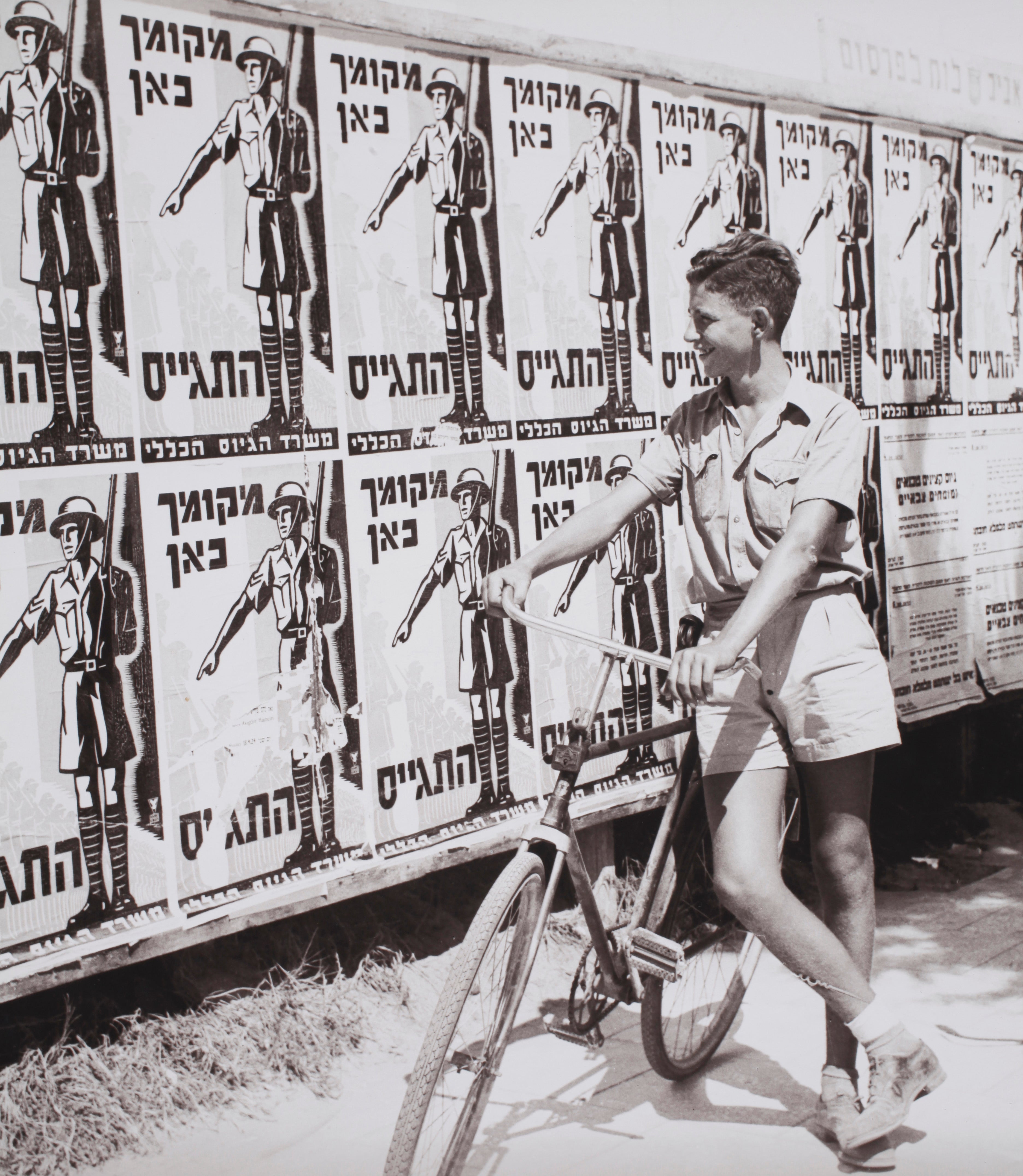 נער מתבונן בלוח מודעות עם כרזה - מקומך כאן התגייס
